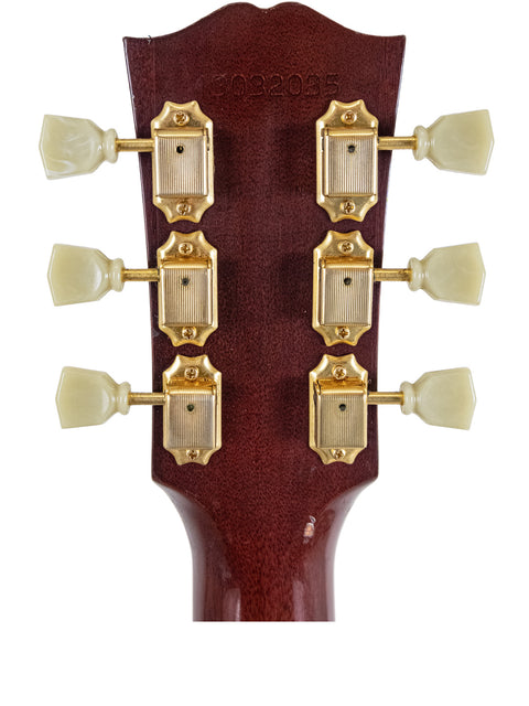 Headstock of a Gibson Hummingbird True Vintage electric guitar featuring elegant gold hardware, showcasing craftsmanship and style.