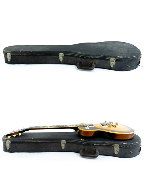Inside a case, two guitars are visible, featuring a vintage 1973 Gibson Les Paul Standard prominently.