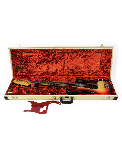 Inside a guitar case, a red and orange vintage Fender Precision Bass from 1972 is displayed, highlighting its unique style.
