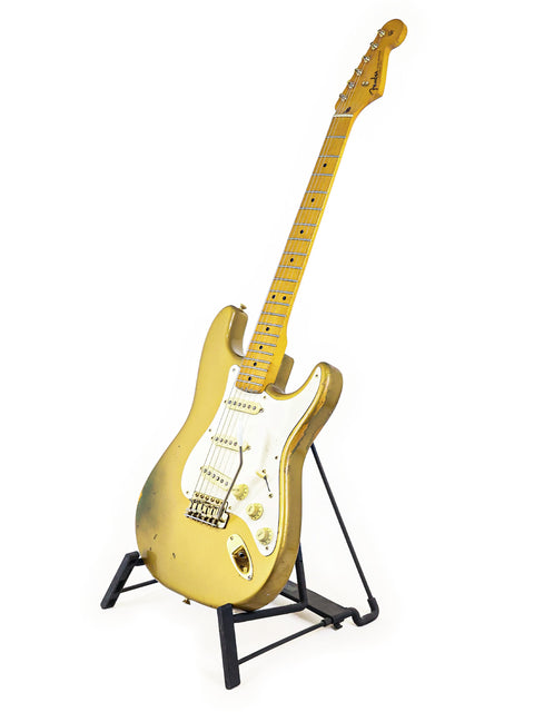 Limited Edition golden guitar on a stand, featuring a '57 Fender Custom Shop Stratocaster design, set against white.