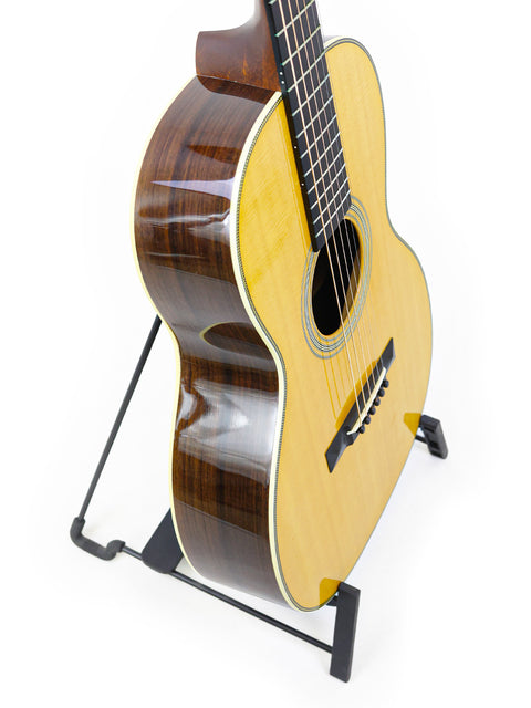 Martin 00-28VS guitar displayed on a stand, set against a bright white backdrop, highlighting its craftsmanship.