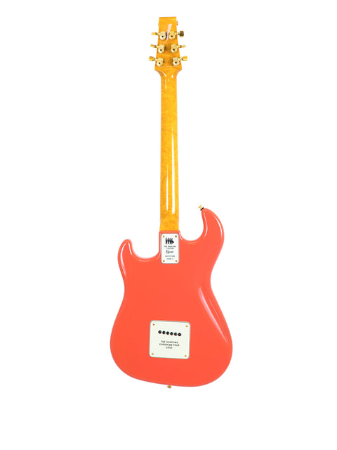 Orange electric guitar with a plaque on its body against a white background.