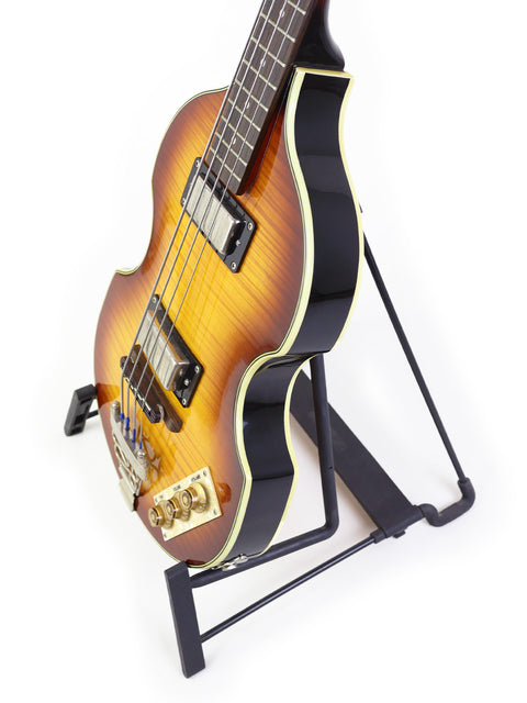 Sunburst electric bass guitar on a black stand against a white background.