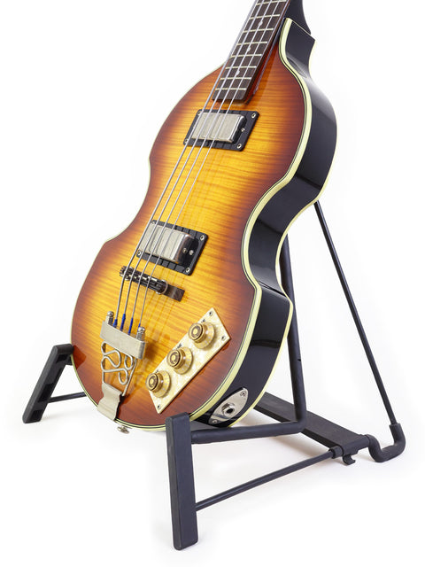 Sunburst electric bass guitar on a stand against a white background.