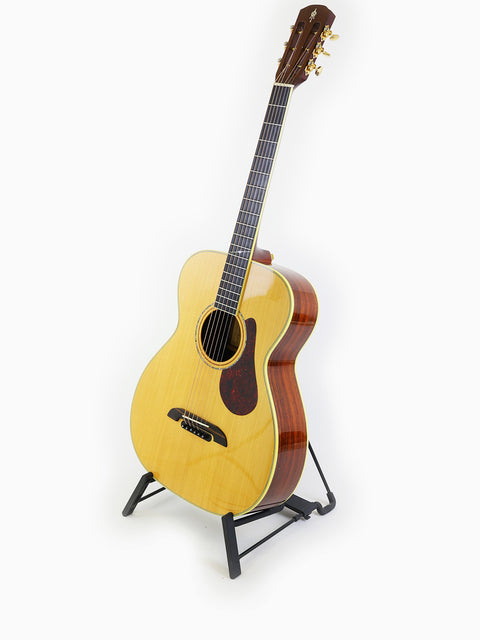 The Alvarez Yairi FYM95V guitar elegantly displayed on a stand, with a pristine white background highlighting its craftsmanship.