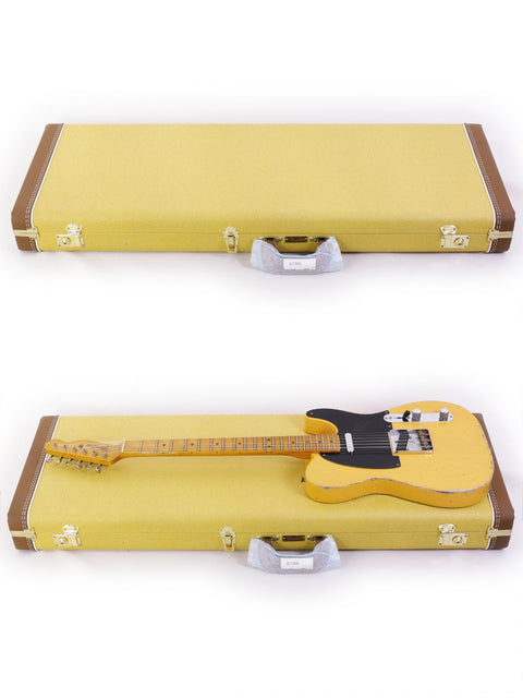 Two yellow guitar cases open to reveal a black and white Fender Carlos Lopez Masterbuilt Nocaster guitar from 2019.