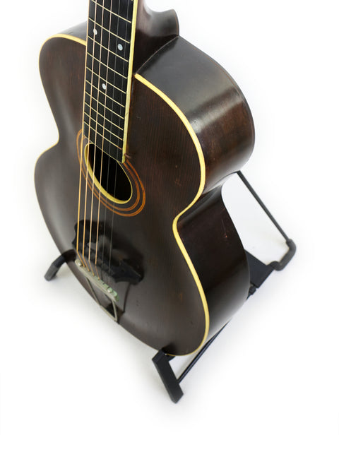 Vintage Gibson L-1 guitar from 1920 on a stand, featuring a simple white background that emphasizes its elegant design.