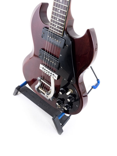 Vintage Gibson SG Pro guitar from 1972 resting on a stand, adorned with a black strap.