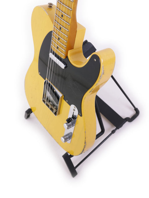 Yellow Fender Carlos Lopez Masterbuilt Nocaster guitar displayed on a stand, equipped with a black strap, USA 2019 edition.