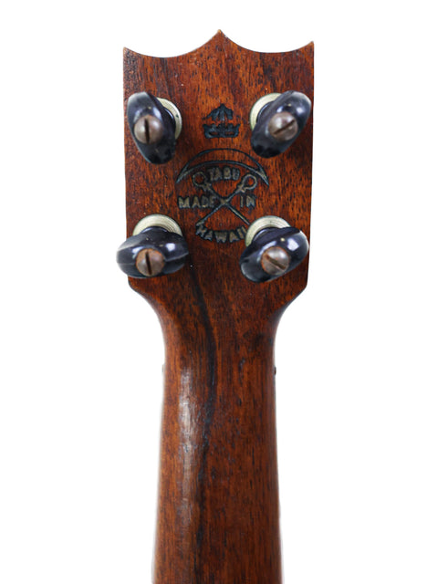 Zoomed-in view of the headstock of a TABU Style 2 "Midget" Koa Ukulele, a classic Hawaiian instrument from 1917.
