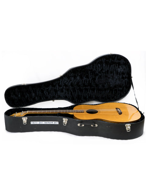black guitar case encasing a wooden-bodied Ernie Ball Earthwood Bass, showcasing its 1980s USA craftsmanship.
