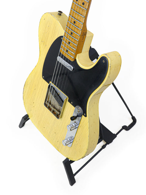 vibrant yellow electric guitar displayed on a stand, featuring the Fender Master Built Carlos Lopez 70th Anniversary model from 2020.