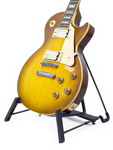 yellow Gibson Les Paul Classic 1960 Reissue guitar on a stand with a sleek black base, showcasing its vibrant color.